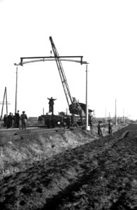 HUA-164320-Afbeelding van het plaatsen van een betonnen bovenleidingsportaal type GP langs de spoorlijn tussen Breda en Tilburg in het kader van de electrificatie van de spoorlijnen in Noord-Brabant