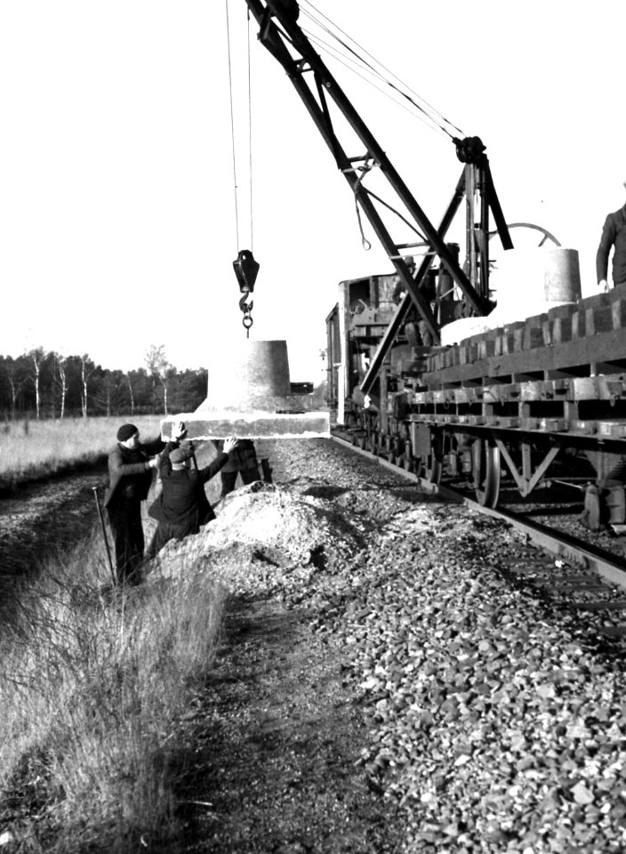 HUA-164317-Afbeelding van het plaatsen van een betonnen voet voor een bovenleidingsmast langs de spoorlijn tussen Breda en Tilburg in het kader van de electrificatie van de spoorlijnen in Noord-Brabant