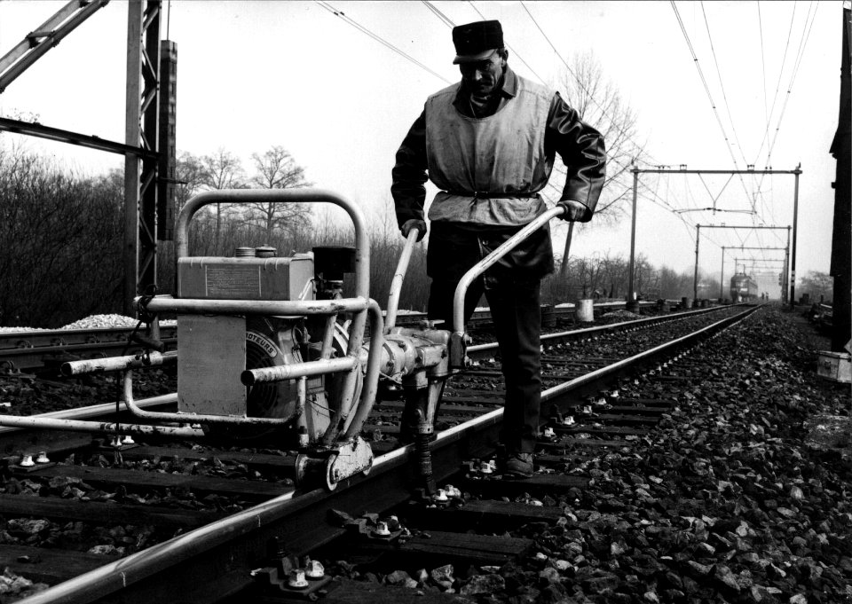 HUA-153413-Afbeelding van een wegwerker van NS met een kraagschroefmachine