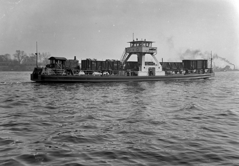 HUA-165616-Afbeelding van de Spoorpont II van Rederij Koppe met enkele goederenwagens en een locomotor (serie 200-300) van de N.S. op het IJ tussen de Rietlanden en Amsterdam Noord