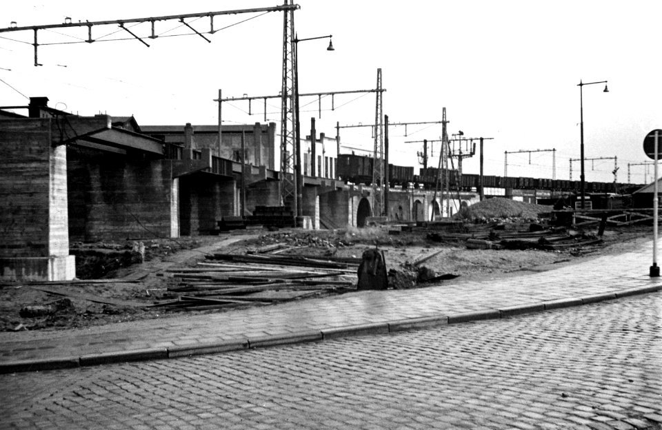 HUA-164282-Gezicht op de herstelwerkzaamheden aan het tijdens de oorlog beschadigde spoorviaduct langs het Hofplein te Rotterdam (spoorlijn tussen de stations D.P. en Beurs). Links op de achtergrond het N.S.-sta