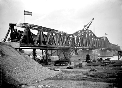 HUA-166383-Gezicht op de van oorlogsschade herstelde spoorbrug over de Maas bij Hedel, met enkele Duitse stoomlocomotieven tijdens een belastingproef