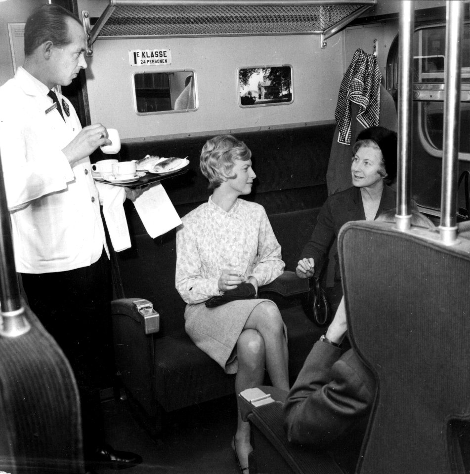 HUA-152872-Afbeelding van twee dames in een trein van de N.S., met links een steward van Wagons-Lits die koffie serveert