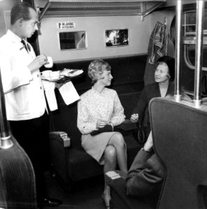 HUA-152872-Afbeelding van twee dames in een trein van de N.S., met links een steward van Wagons-Lits die koffie serveert
