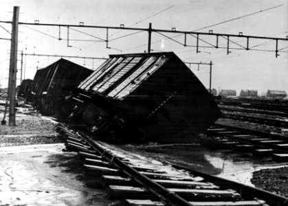 HUA-152840-Afbeelding van verzakte goederenwagens op het deels weggespoelde en overstroomde emplacement bij Lage Zwaluwe kort na de watersnoodramp