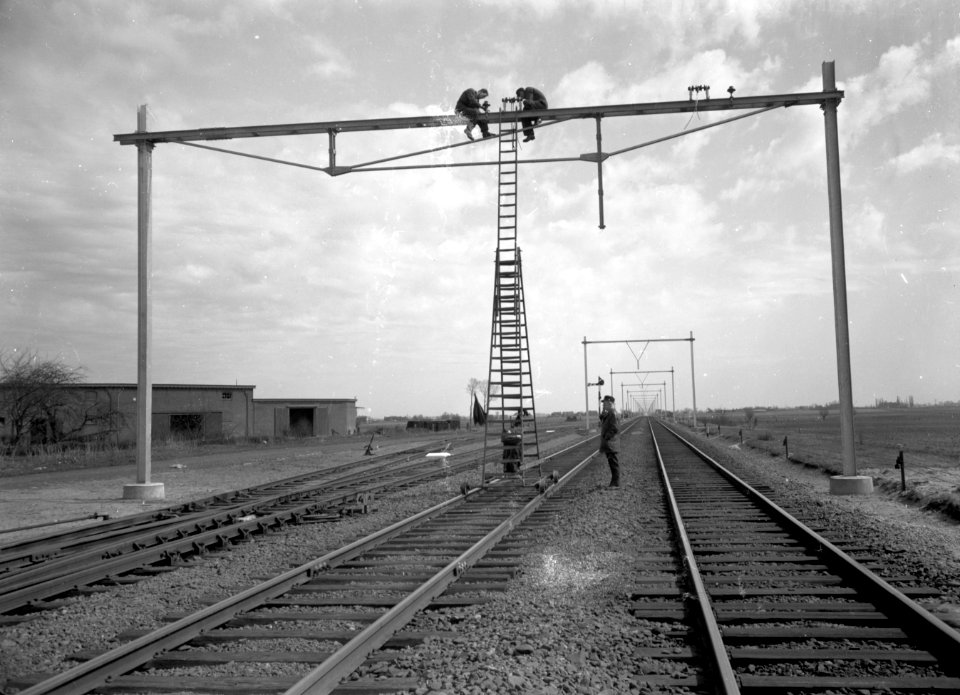 HUA-166430-Afbeelding van het plaatsen van isolatoren op de bovenleidingsportalen te Wouw, ten behoeve van de electrificatie van de spoorlijn Roosendaal-Vlissingen