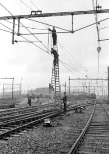 HUA-166466-Afbeelding van werkzaamheden aan de bovenleiding met behulp van een rolladder op het emplacement Dijksgracht te Amsterdam