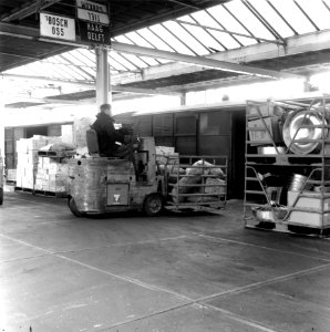 HUA-166336-Afbeelding van het beladen van een goederenwagen met stukgoederen met behulp van een heftruck in de goederenloods van Van Gend & Loos te Zwolle