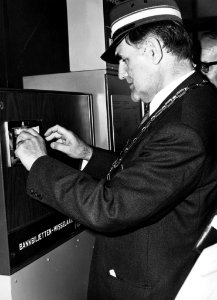 HUA-165601-Afbeelding van de officiële opening van het N.S.-station Waddinxveen Noord te Waddinxveen, met waarnemend burgemeester en wethouder P. Lips (met conducteurspet) die een in de abri geplaatste wisselaut