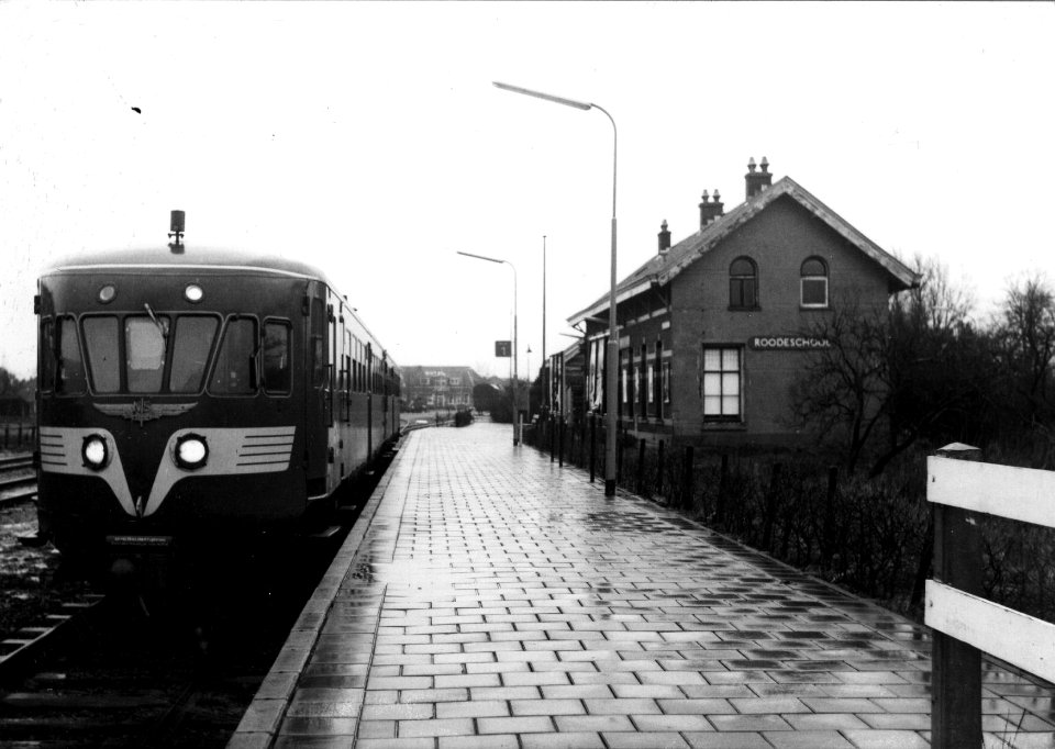 HUA-153210-Afbeelding van een diesel-electrisch treinstel DE 2 ("Blauwe Engel") langs het perron van het N.S.-station Roodeschool te Roodeschool met rechts het oude stationsgebouw kort voor de afbraak