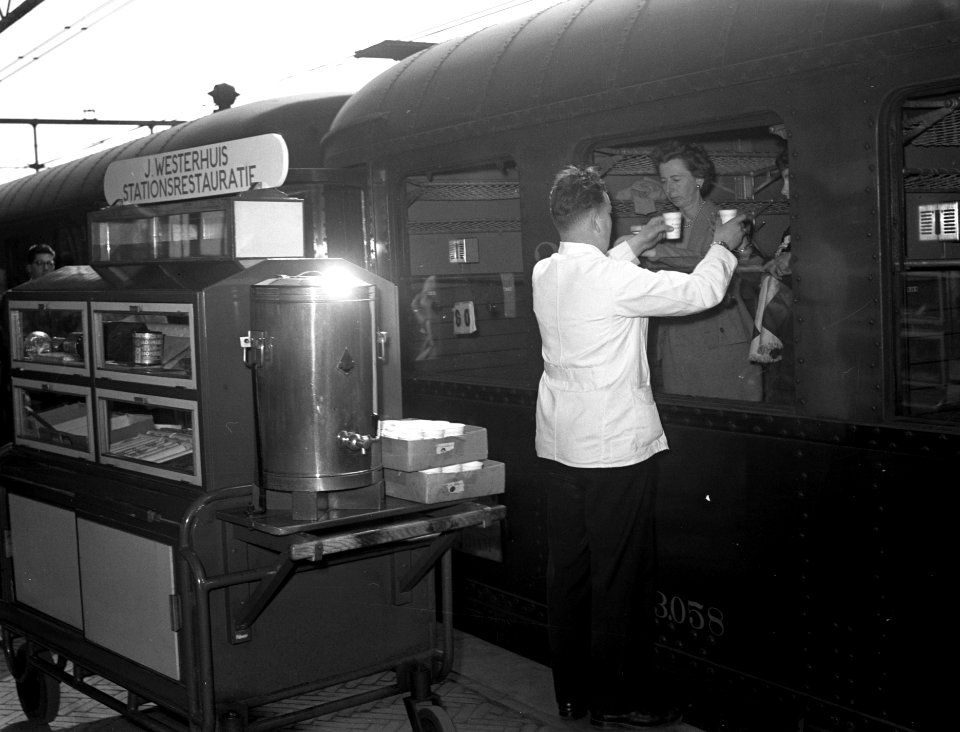 HUA-153788-Afbeelding van de verkoop van koffie op het perron van het NS station Arnhem te Arnhem Links het koffiekarretje van J Westerhuis stationsrestaurateur