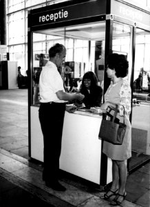 HUA-153356-Afbeelding van een receptioniste van N.S. in de hal van het N.S.-station Rotterdam C.S. te Rotterdam