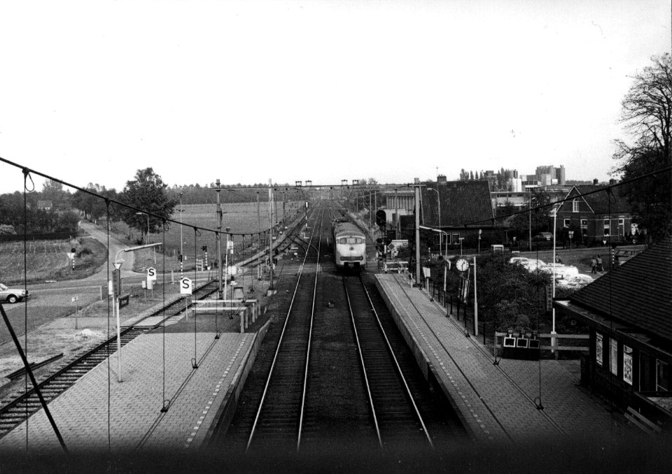 HUA-153293-Gezicht vanaf de voetgangersbrug op de sporen en de perrons van het N.S.-station Putten te Putten. In het midden een electrisch treinstel mat. 1964 (plan V) van de N.S. als stoptrein naar Zwolle