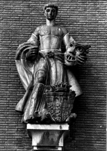 HUA-153979-Detail van de voorgevel van het N.S.-station 's-Hertogenbosch te 's-Hertogenbosch- charmottebeeld van een man met een masker en het wapen van de stad 's-Hertogenbosch, door J. Uiterwaal