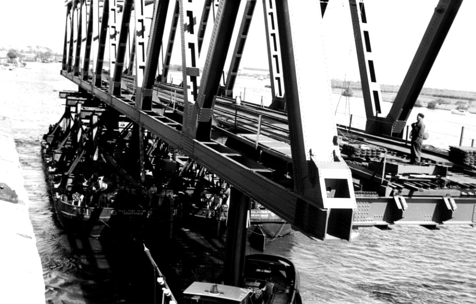 HUA-164389-Afbeelding van het transport van een een brugdeel, bestemd voor de spoorbrug over het Hollands Diep bij Moerdijk, van Dordrecht naar Moerdijk, tijdens het passeren van de spoorbrug over de Beneden Mer