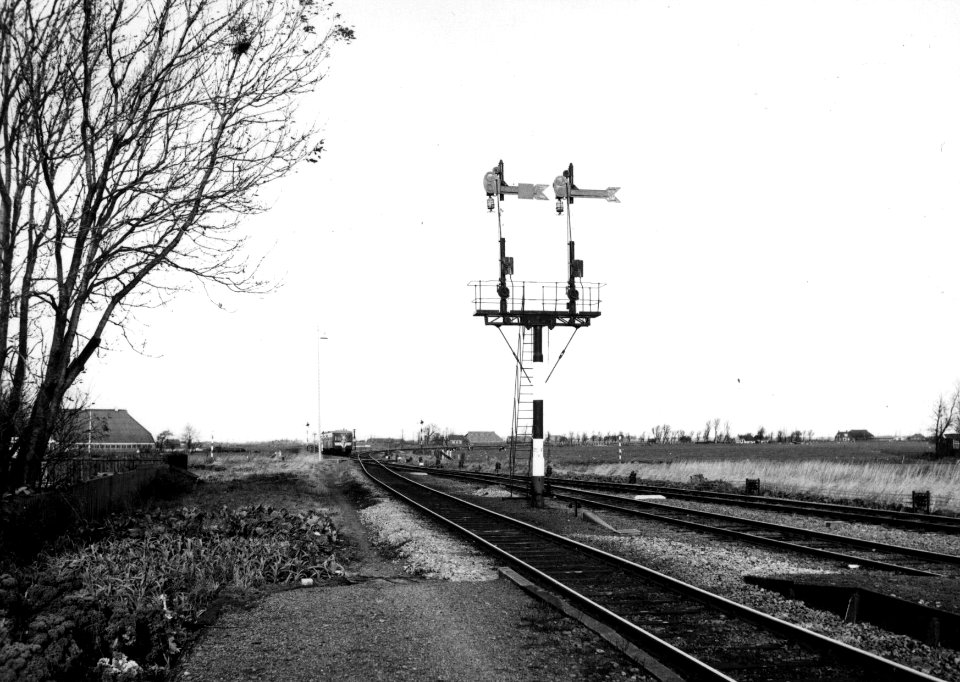 HUA-153906-Afbeelding van een tweevoudig vertakkingssein bij het NS station Sauwerd te Sauwerd Op de achtergrond een diesel electrisch treinstel DE 2 Blauwe Enge