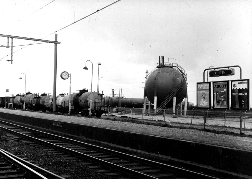 HUA-153205-Gezicht op een gashouder van de firma Benegas met links enkele ketelwagens Op de voorgrond het 2e perron van het NS station Putten te Putten