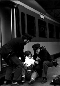 HUA-153325-Afbeelding van twee behulpzame beambten van de spoorwegpolitie bij een uit de trein gevallen vrouw