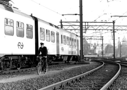 HUA-153326-Afbeelding van een beambte van de spoorwegpolitie op de fiets op het emplacement te Amsterdam C.S