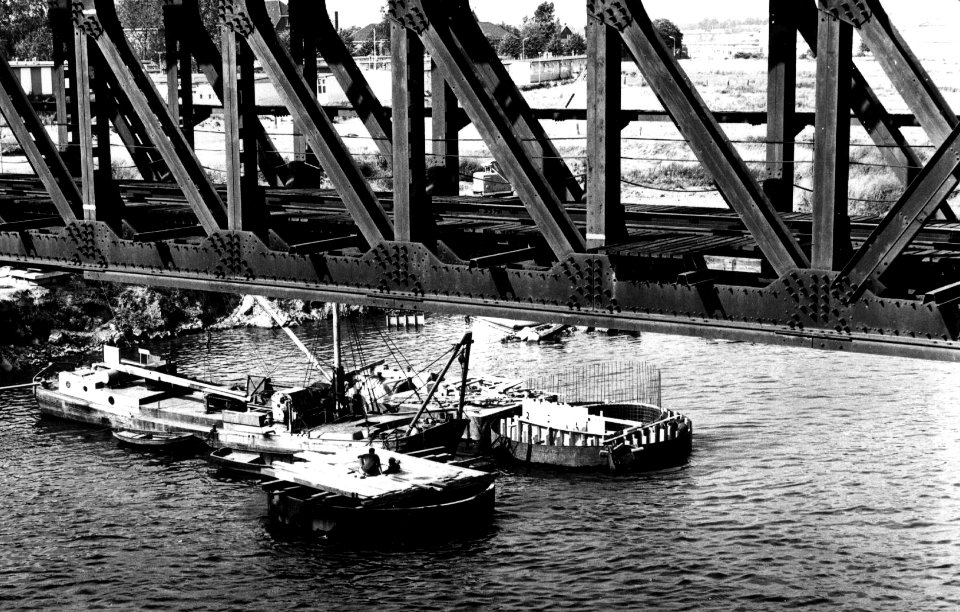 HUA-153620-Gezicht op de bouw van pijlers voor de nieuwe spoorbrug over de Maas bij Venlo met op de voorgrond de oude noodbrug