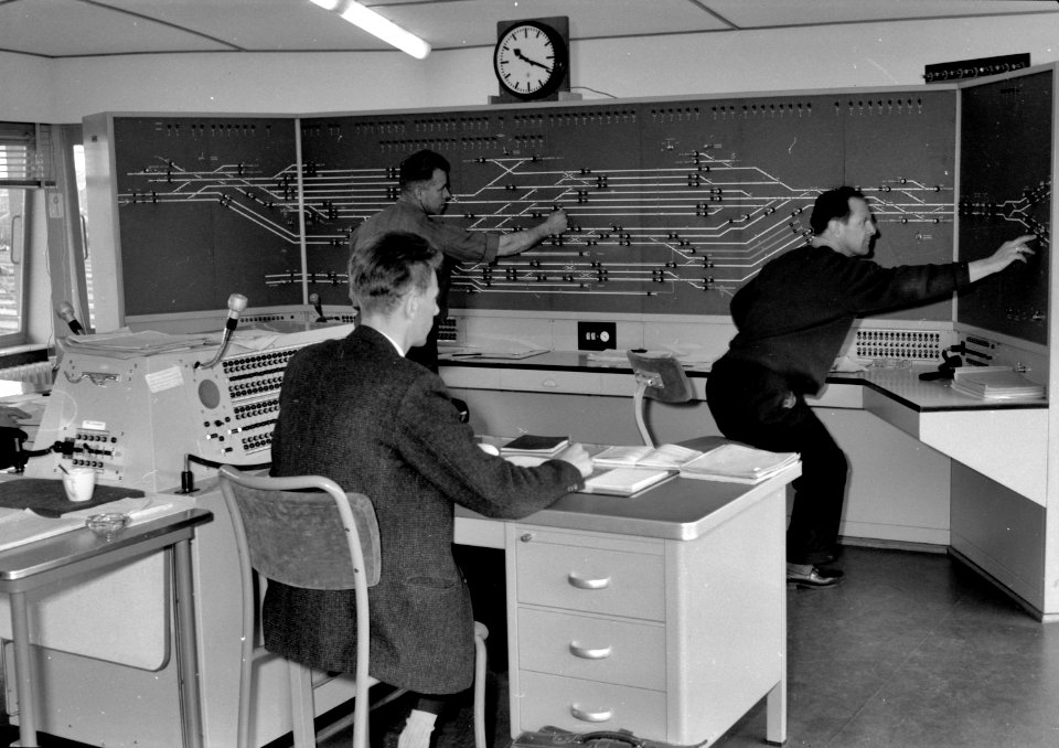 HUA-159643-Afbeelding van de treindienstleiders bij het NX-bedieningstableau in het seinhuis (NX-post) van de N.S. te Amersfoort