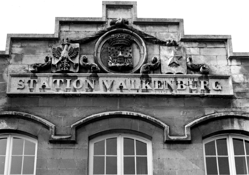 HUA-153966-Gezicht op het bovenste deel van de voorgevel van het N.S.-station Valkenburg te Valkenburg voorstellende de wapens van Aken (rechts), Valkenburg (midden) en Maastricht (links)