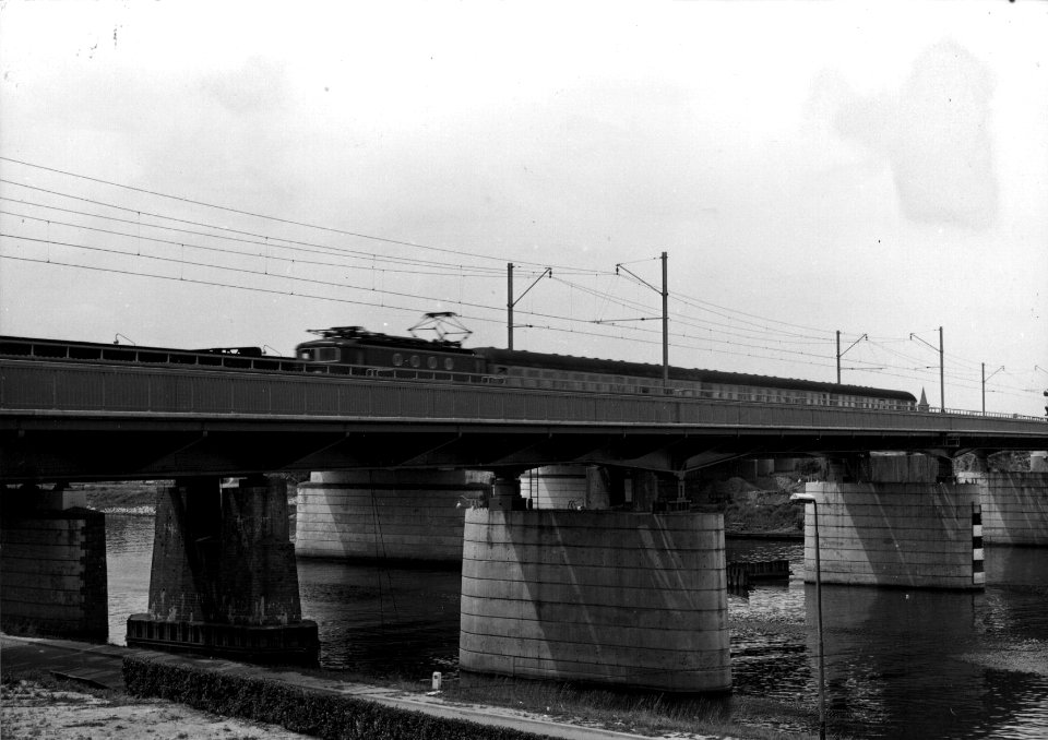 HUA-153626-Gezicht op de nieuwe spoorbrug over de Maas bij Venlo met een internationale trein getrokken door een electrische locomotief uit de serie 1100 van de N.S