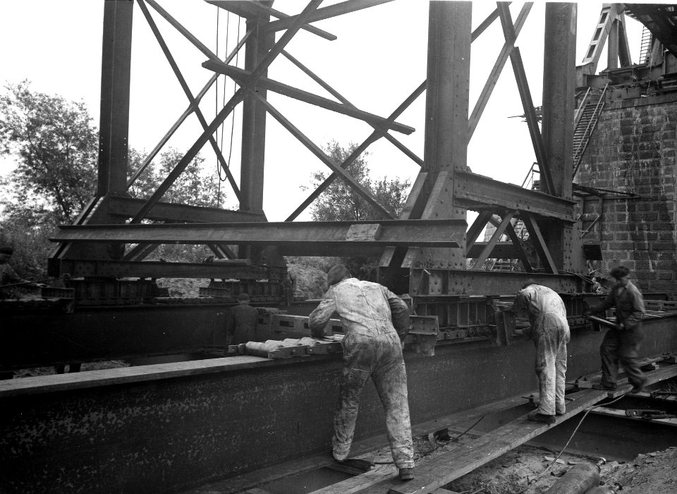 HUA-163924-Afbeelding van bouwvakkers tijdens het inrollen van een brugdeel ten behoeve van de herbouw van de spoorbrug over de Waal te Zaltbommel