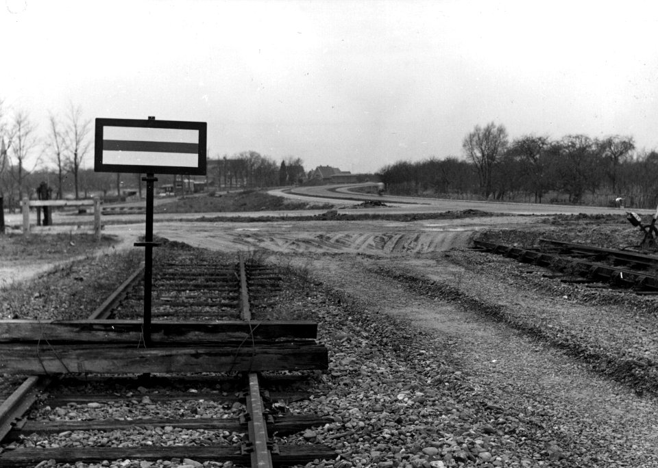 HUA-153939-Afbeelding van een stopbord van de N.S. op het emplacement te Kesteren. Op de achtergrond het tracé van de opgebroken spoorlijn naar Rhenen