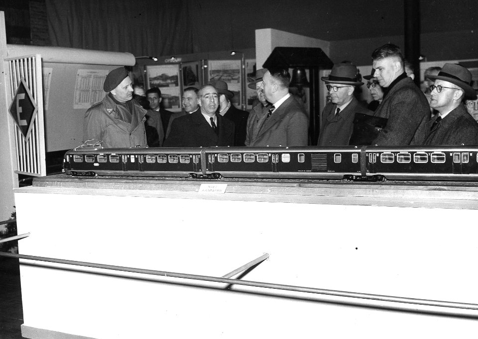 HUA-163906-Afbeelding van een model van het electrische treinstel nr. 412 (mat. 1936) van de N.S. op een stand van de N.S. tijdens een tentoonstelling of beurs te Tilburg, met tweede van rechts de heer Vet, Chef