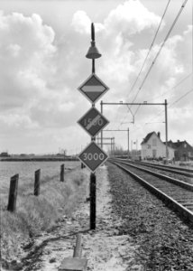 HUA-153941-Afbeelding van waarschuwingsborden van de N.S. voor overgang van het Nederlandse stroomsysteem naar het Belgische bij Roosendaal. Op de achtergrond wachtpost 21