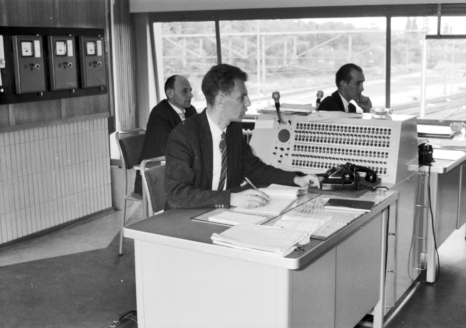 HUA-159641-Afbeelding van de treindienstleider B.J. Ambergen in het seinhuis (NX-post) van de N.S. te Amersfoort, met achter hem seinhuiswachters G.J. van Wilpen en L.A. Dons