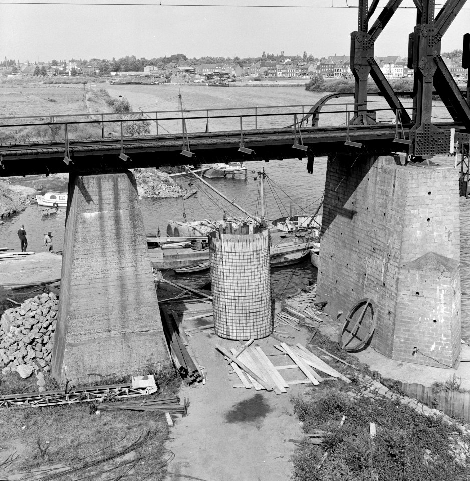 HUA-153621-Gezicht op de bouw van een pijler voor de nieuwe spoorbrug over de Maas bij Venlo met op de voorgrond de oude noodbrug