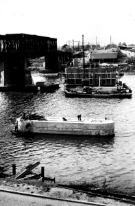 HUA-153622-Gezicht op de bouw van de pijlers voor de nieuwe spoorbrug over de Maas bij Venlo met links de oude noodbrug