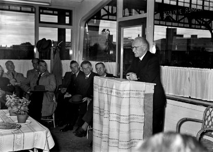 HUA-167267-Afbeelding van N.S.-architect ir. H.G.J. Schelling tijdens zijn toespraak bij de opening van het nieuwe N.S.-station Hengelo te Hengelo, in de wachtkamer 3e klasse van het station