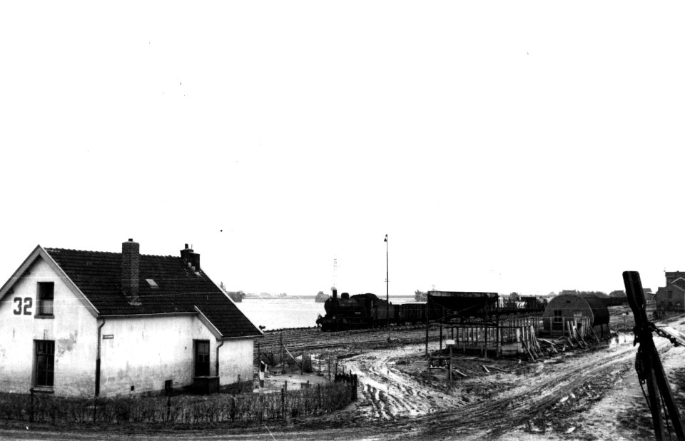 HUA-160432-Afbeelding van een goederentrein bij het N.S.-station Kruiningen-Yerseke te Kruiningen, tijdens de herstellingswerkzaamheden na de Watersnoodramp van 1953. Links wachtpost 32