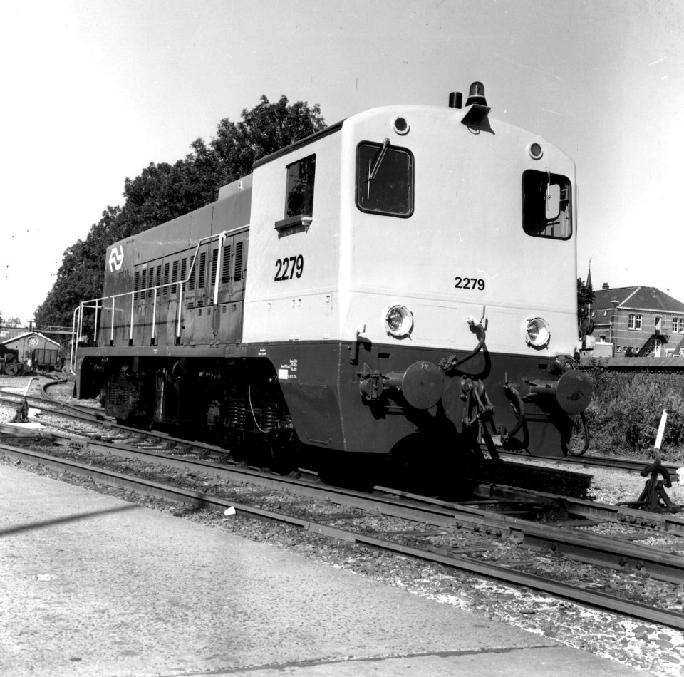 HUA-166581-Afbeelding van de diesel-electrische locomotief nr. 2279 (serie 2200-2300) van de N.S. in de nieuwe geel-grijze huisstijl op het terrein van de Hoofdwerkplaats van de N.S. te Tilburg