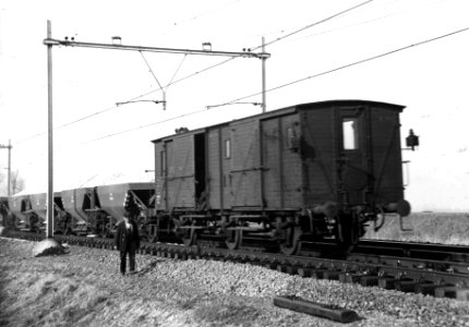 HUA-163824-Afbeelding van het storten van ballast met onderlossers van de N.S. bij Abcoude, met een verblijfswagen voor het personeel, tijdens de werkzaamheden ten behoeve van de baanverzwaring tussen Amsterdam 