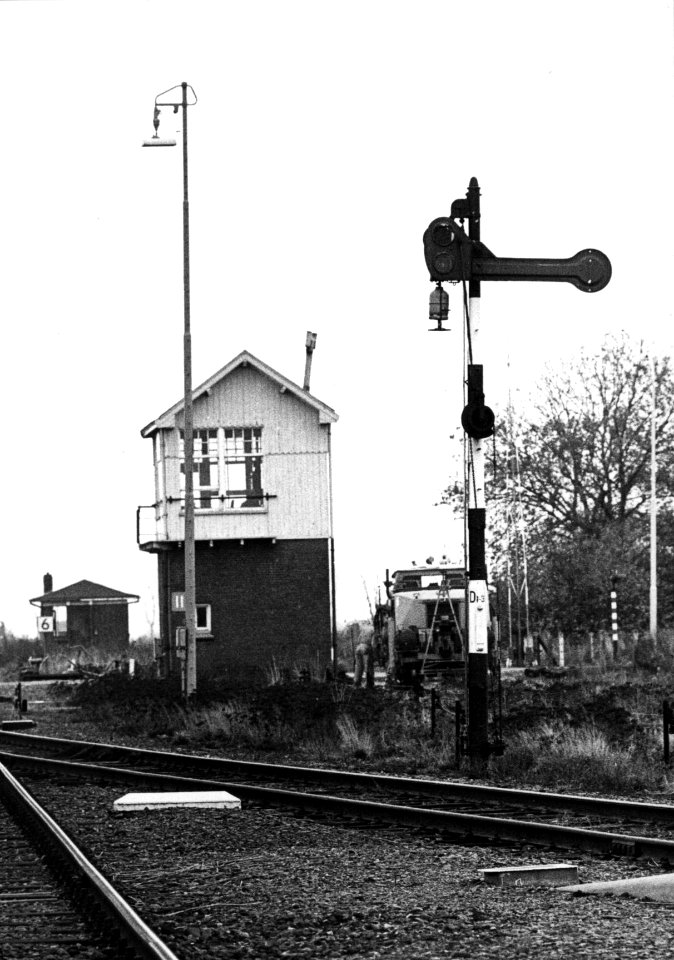 HUA-157366-Afbeelding van een klassiek armsein op het emplacement van het N.S.-station Nieuweschans te Nieuweschans. Daarachter het seinhuis Post II en op de achtergrond de brugpost van de draaibrug over de Westerwoldse A