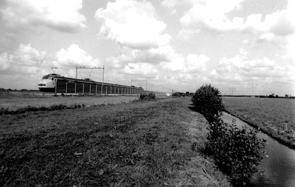 HUA-167175-Afbeelding van de proefopstelling van een geluidsscherm langs de spoorlijn ten westen van Woerden (nabij Oudewater), met een passerend electrisch treinstel mat. 1954 van de N.S