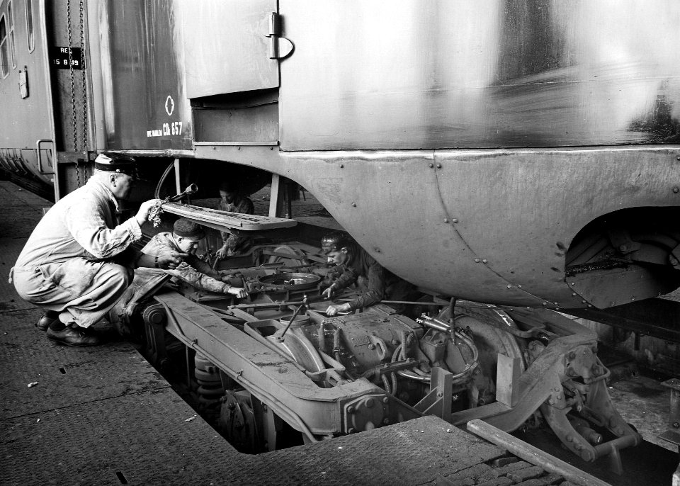 HUA-163904-Afbeelding va een aantal monteurs tijdens werkzaamheden aan het draaistel van de CDk-bak van het electrische treinstel nr. 657 (mat. 1946) van de N.S. in de revisieloods van de werkplaats Zaanstraat t
