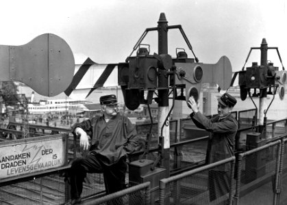 HUA-166977-Afbeelding van Wim Kan (rechts) van het ABC-Cabaret op de seinbrug bij het N.S.-station Amsterdam C.S. te Amsterdam, tijdens het poetsen van de glazen in de seinarmen, met links een onbekend lid van h