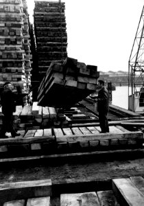 HUA-159365-Afbeelding van twee werknemers van de Houtbereidingsinrichting van de N.S. te Dordrecht tijdens het lossen van hout op de kade