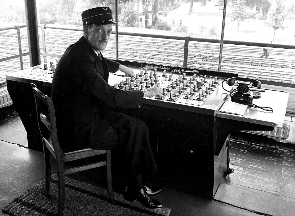 HUA-163921-Afbeelding van één van de leden van het ABC-Cabaret als seinhuiswachter in het seinhuis van de N.S. te Haarlem. N.B. De foto is gemaakt in het kader van de promotie van het programma "De A.B.C.-Expres