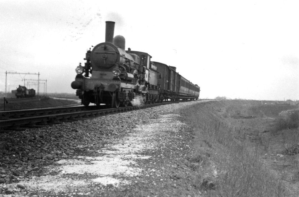HUA-160562-Afbeelding van een stoomlocomotief uit de serie 1700-1800 van de N.S. met een reizigerstrein uit Mariënberg te Almelo, ter hoogte van de aansluiting met de lijn Deventer-Almelo