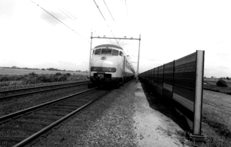 HUA-167176-Afbeelding van de proefopstelling van een geluidsscherm langs de spoorlijn ten westen van Woerden (nabij Oudewater), met een passerende trein bestaande uit electrische treinstellen mat. 1964 (plan V) 