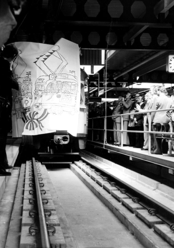 HUA-165555-Afbeelding van de opening van het tramplateau boven het NS station Den Haag CS te Den Haag door een tram die door een papieren scheidingswand rijdt