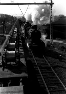 HUA-160521-Afbeelding van een goederentrein getrokken door twee stoomlocomotieven uit de serie 3700 3800 van de NS gezien vanaf een bovenleidingsmontagewagen tij