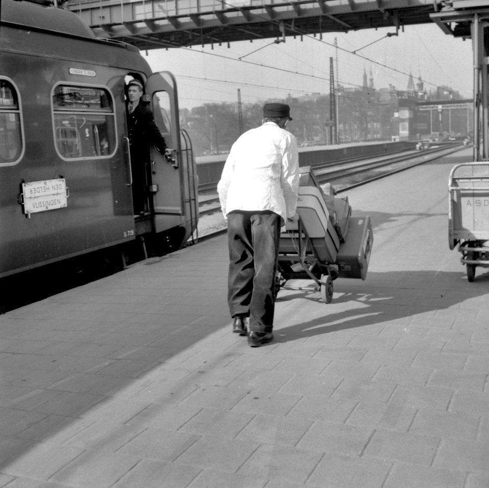 HUA-166729-Afbeelding van een kruier op het perron van het N.S.-station Amsterdam C.S. te Amsterdam, met links een machinist in de deuropening van het electrische treinstel nr. 729 (mat. 1954, plan F) van de N.S