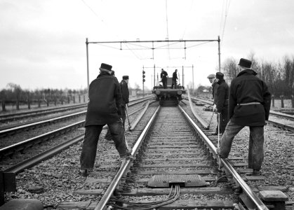 HUA-167436-Afbeelding van wegwerkers van de NS tijdens het lossen van spoorstaven op de spoorlijn nabij Putten